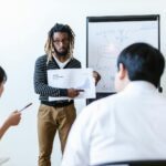 Business team in a modern Dubai office discussing VARA cryptocurrency legal documents and blockchain strategies with city skyline skyscrapers visible