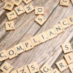 Switzerland crypto license regulatory compliance concept illustrated by wooden tiles forming 'COMPLIANCE' – representing FINMA and SRO financial regulation for blockchain and fintech offices