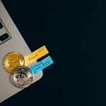 UK crypto license compliance paperwork with Bitcoin coins on laptop and investment notes reflecting FCA registration and digital assets law office